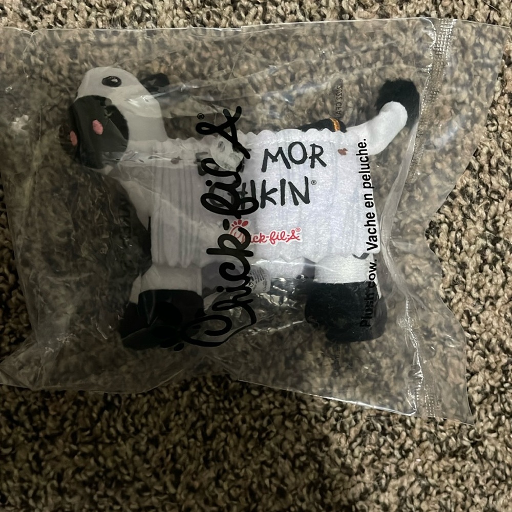Chick-Fila cow with a “Eat Mor Chikin” sign hanging on him. Plush